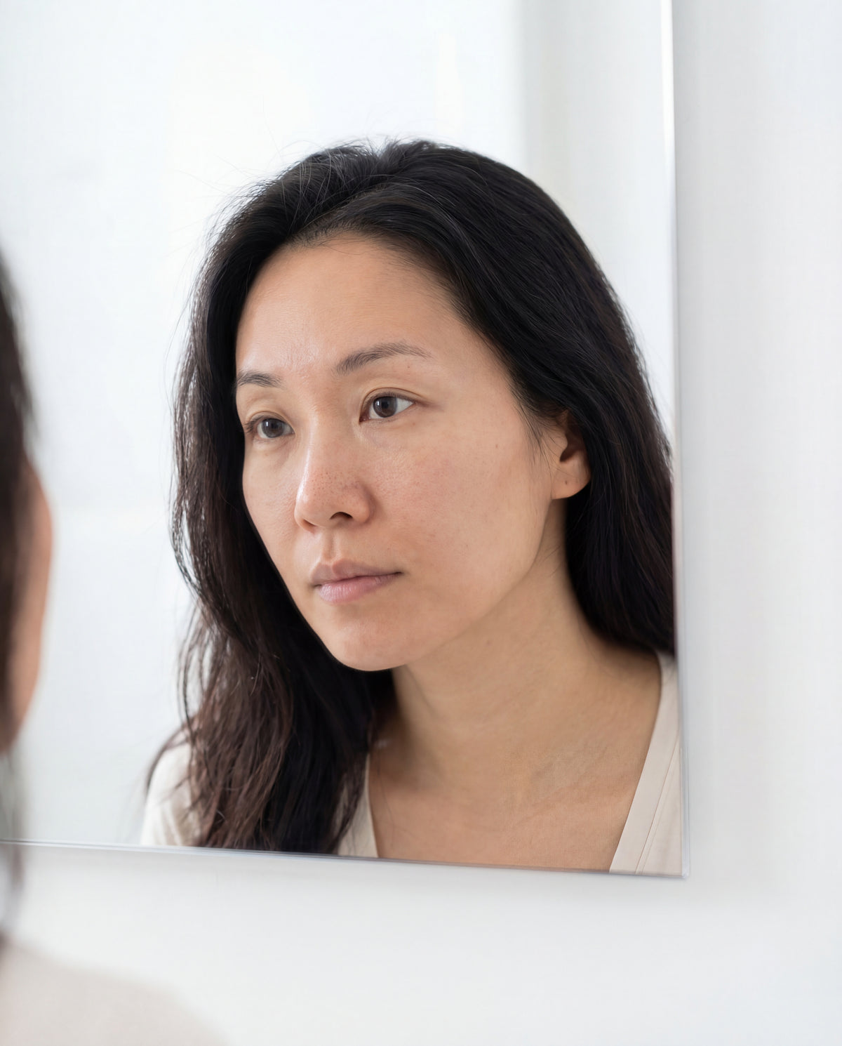 Woman meticulously examines her skin in search of glass skin — exosome mask hydration glow K-Beauty